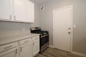 Oakland apartment for rent - a kitchen with white cabinets and a stove and a door
