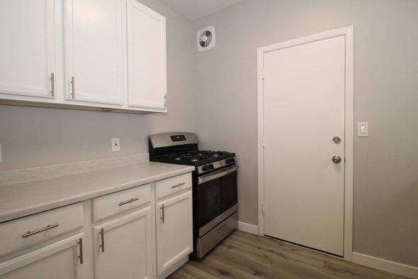Oakland apartment for rent - a kitchen with white cabinets and a stove and a door