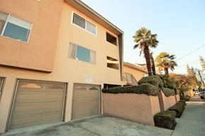 Oakland apartment for rent - a building with a garage and palm trees in front of it