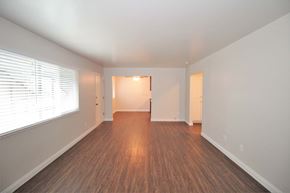 Oakland apartment for rent - an empty living room with a large window and wood flooring