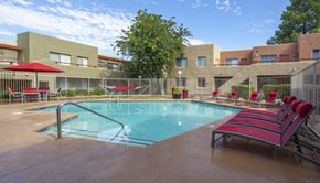 Tucson apartment for rent - A pool with red chairs and a building in the background.