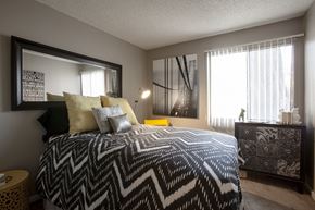 Tucson apartment for rent - A bedroom with a patterned bedspread and a large mirror on the wall.