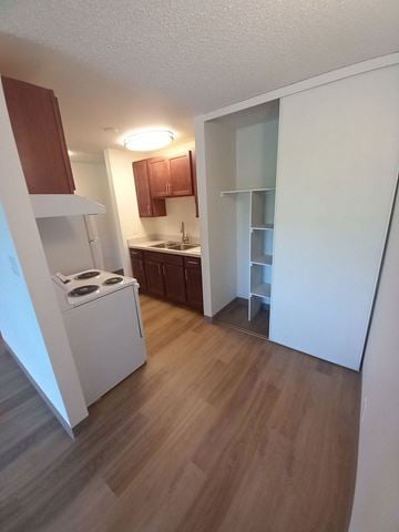 Bozeman apartment for rent - A small kitchen with a stove top oven and wooden floors.