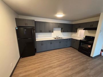 Bozeman apartment for rent - A kitchen with black appliances and wooden floors.