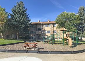 Bozeman apartment for rent - A playground with a slide, picnic table, and a building in the background.