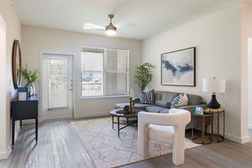 Burleson apartment for rent - A living room with a grey couch, a white chair, and a painting on the wall.