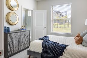 Burleson apartment for rent - A bedroom with a bed, a dresser, and two round mirrors on the wall.