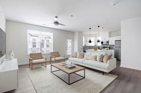Burleson apartment for rent - A modern living room with a white couch, wooden chairs, and a coffee table.