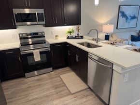 Corinth apartment for rent - A modern kitchen with dark brown cabinets and stainless steel appliances at Arden at Corinth, Corinth, Texas