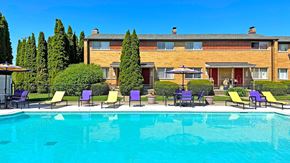 Midland apartment for rent - A swimming pool in front of a building with chairs around it.