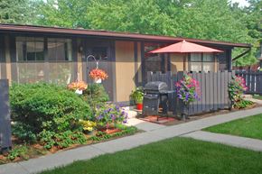 Toledo apartment for rent - A house with a brown and tan exterior has a red umbrella on the patio.