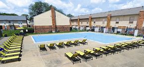 Grand Blanc apartment for rent - A pool surrounded by sun loungers and a brick building.