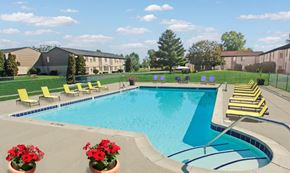 Howell apartment for rent - A swimming pool surrounded by yellow lounge chairs and red flowers.