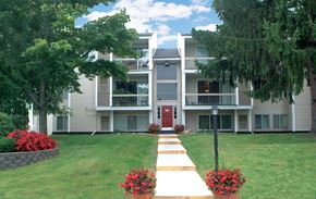 Flint apartment for rent - A building with a red door and a walkway with red flowers in front.
