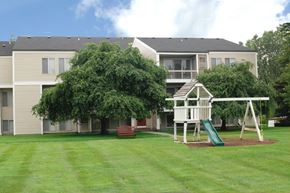 Flint apartment for rent - A playground with a slide and a swing set in front of a building.