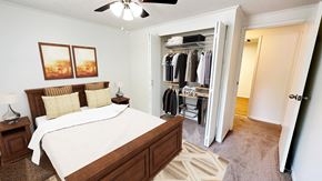 Ann Arbor apartment for rent - A bedroom with a large bed and a closet with clothes hanging.