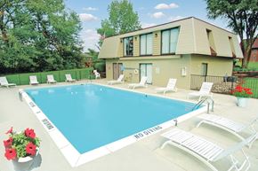 Kentwood apartment for rent - A pool with chairs and a house in the background.