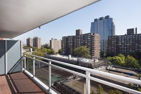 New York apartment for rent - A balcony overlooks a cityscape with a mix of residential and commercial buildings.