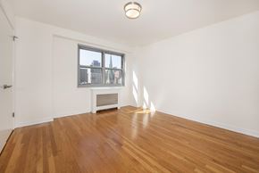 New York apartment for rent - A room with wooden floors and a window overlooking a cityscape.