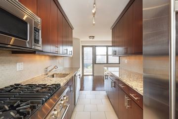 New York apartment for rent - A modern kitchen with dark wood cabinets and stainless steel appliances.