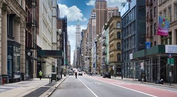 New York apartment for rent - A city street with buildings on both sides and a few pedestrians walking.