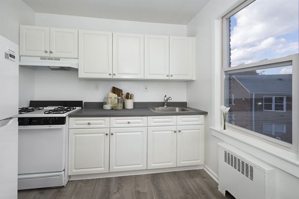 Dobbs Ferry apartment for rent - A kitchen with white cabinets and a black stove top.