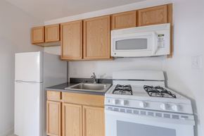 Dobbs Ferry apartment for rent - A white stove and sink in a kitchen with wooden cabinets.