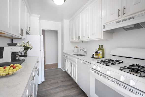 Long Beach apartment for rent - A white kitchen with a stove and a bowl of fruit on the counter.
