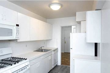 Long Beach apartment for rent - A white kitchen with a stove, microwave, and refrigerator.
