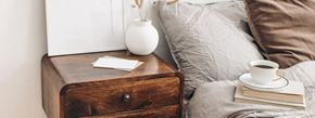 Queens apartment for rent - A wooden nightstand with a cup of coffee and a book on top of it.