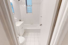 Queens apartment for rent - A white bathroom with a tub, toilet, and sink.