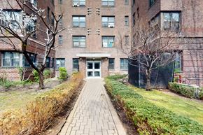 New York apartment for rent - A brick building with a pathway leading to the entrance.