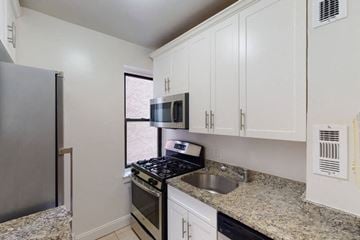 New York apartment for rent - A kitchen with granite countertops and white cabinets.