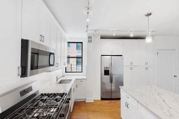 New York apartment for rent - A modern kitchen with white cabinets and a stainless steel refrigerator.
