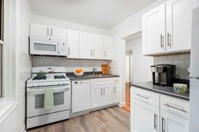 White Plains apartment for rent - A white kitchen with a stove, microwave, and refrigerator.
