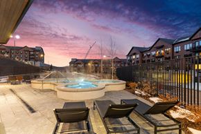 Park City apartment for rent - A hot tub sits in the middle of a patio with chairs around it.