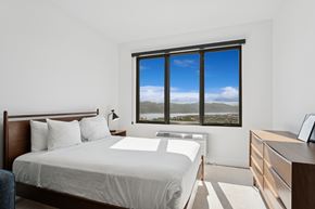 Park City apartment for rent - A bedroom with a large bed and a view of the mountains outside the window.