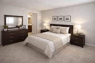 Sacramento apartment for rent - A bedroom with a large bed, a dresser, and a nightstand with a lamp.