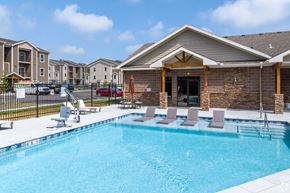 Kansas City apartment for rent - A swimming pool with lounge chairs and a building in the background.