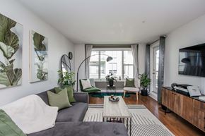 Halifax apartment for rent - A living room with a grey couch, a coffee table, and a large window.
