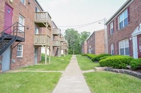 St. Louis apartment for rent - A long concrete walkway leads between two rows of red brick apartment buildings.