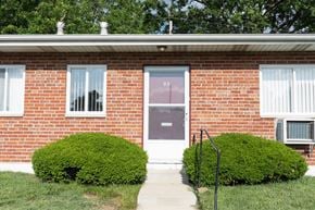 Overland apartment for rent - A red brick house with a purple door and two green bushes.