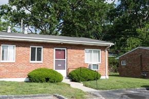 Overland apartment for rent - A red brick house with a black fence and green bushes.