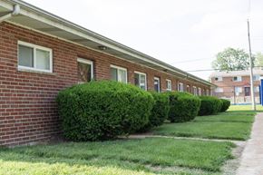 Overland apartment for rent - A red brick building with green bushes in front.