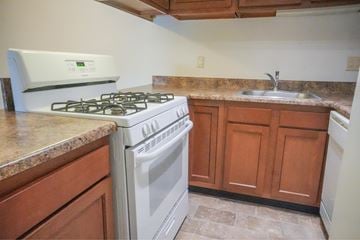 Black Jack apartment for rent - A white oven and stove top are in a kitchen with brown cabinets.