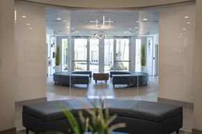 Hialeah apartment for rent - A spacious waiting area with a bench in the foreground and a view of a lounge area through the glass wall.