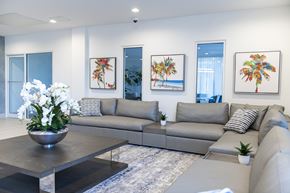 Hialeah apartment for rent - A modern living room with a grey sofa, a coffee table, and three framed pictures on the wall.