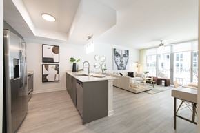 Miami apartment for rent - A modern kitchen with a refrigerator, sink, and a dining area with a table and chairs.