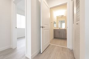 Miami apartment for rent - A white hallway with a mirrored doorway leading to a bedroom.