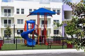 Miami apartment for rent - A playground with a blue slide and a red slide in front of a white building.